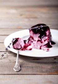 Blackcurrant ice cream on a white plate with a piece of ice-crea