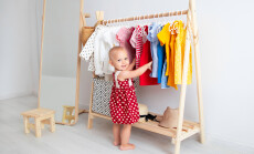 Baby,Girl,Stands,Near,A,Wardrobe,And,Chooses,A,Dress