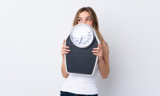Young,Woman,Over,Isolated,White,Background,With,Weighing,Machine,And