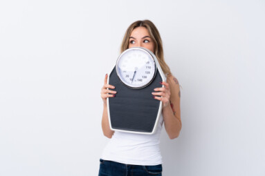 Young,Woman,Over,Isolated,White,Background,With,Weighing,Machine,And