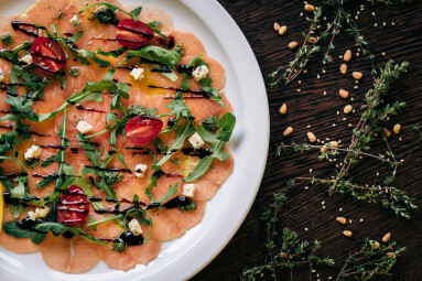 Salmon,Carpaccio,In,A,White,Plate,On,A,Wooden,Table