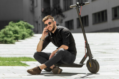 Young,Man,Riding,Electric,Scooter,In,Urban,Background