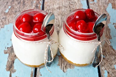 Two,Delicious,Cherry,Cheesecake,In,Mason,Jars,With,Spoons,On