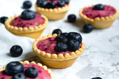 Sweet,Mini,Tartlets,With,Cream,And,Berries,On,White,Textured