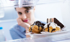 Young,Hungry,Woman,In,Front,Of,Refrigerator,Craving,Chocolate,Pastries.