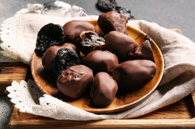 Delicious,Chocolate,Candies,With,Prunes,In,Plate,On,Wooden,Board,