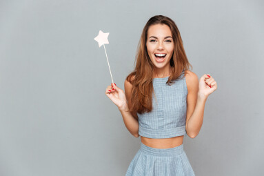Happy,Amazed,Young,Woman,Holding,Magic,Wand,Over,Grey,Background
