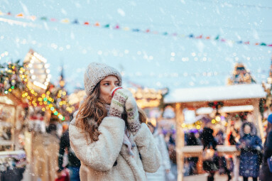 Girl,Drinking,Hot,Coffee,While,Walking,In,Christmas,Market,Decorated