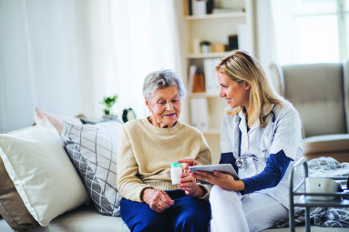 A,Health,Visitor,With,Tablet,Explaining,A,Senior,Woman,How