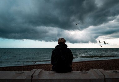 Lonely man looking at the sea and storm clouds