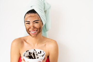 Young,Smiling,Woman,Applying,Coffee,Scrub,Mask,On,Face,-