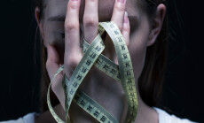 Anorexic,Girl,Covering,Her,Face,With,A,Centimeter
