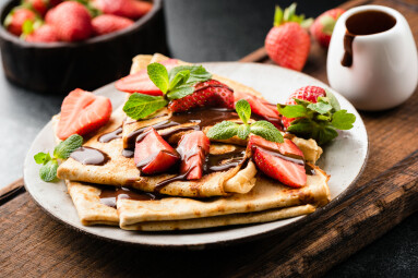 French,Crepes,With,Strawberries,And,Chocolate,Sauce,On,A,Plate