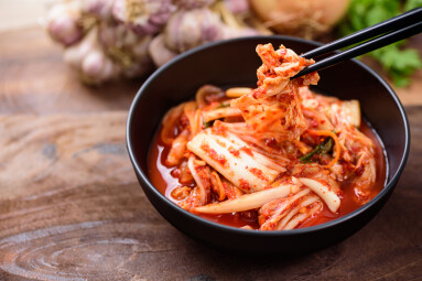 Eating,Kimchi,Cabbage,In,A,Bowl,With,Chopsticks,,Korean,Food