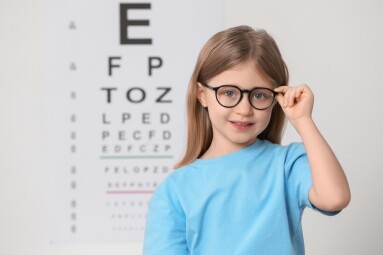 Little,Girl,With,Glasses,Against,Vision,Test,Chart