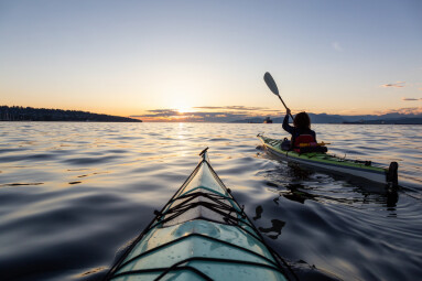 Girl Sea Kayaking during a vibrant sunny summer sunset