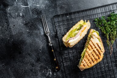 Grilled,Panini,With,Prosciutto,Ham,,Salad,And,Cheese.,Black,Background.