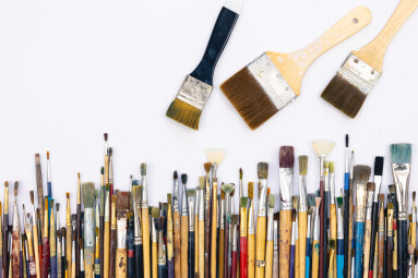 Many brushes for painting on a white background, top view.