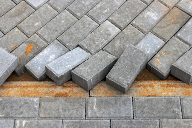 Pavement repairs and paving slabs laying on the prepared surface, with tile cubes in the background. Laying paving slabs in the pedestrian zone of the city. Paving slabs and curbs.