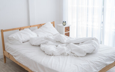 White messy bed in a white room in morning without people