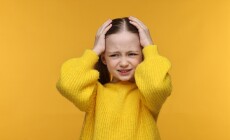 Little,Girl,Suffering,From,Headache,On,Yellow,Background