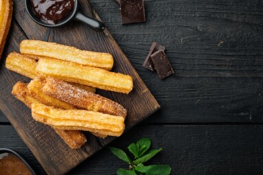 Churros,With,Caramel,,Traditional,Spanish,Cusine,,On,Black,Wooden,Table