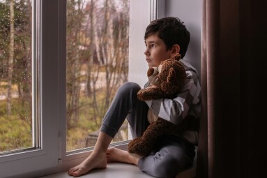 A,Sad,Boy,Looks,Out,The,Window,,Hugging,A,Teddy