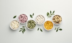 Different,Vitamin,Capsules,In,Bowls,And,Leaves,On,White,Background,