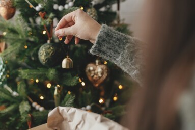 Hands,Decorating,Christmas,Tree,With,Stylish,Bauble,In,Atmospheric,Festive