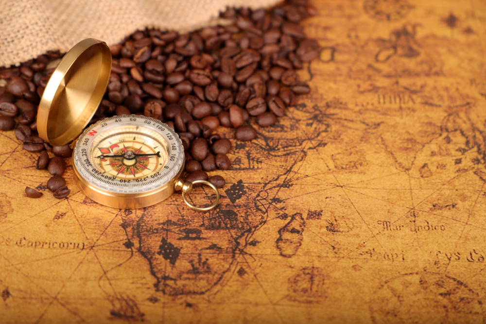 Coffee,Beans,And,Vintage,Compass,On,An,Old,World,Map