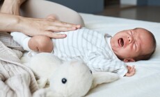 Unrecognizable,Woman,Massaging,Tummy,Of,Her,Crying,Sick,Son,Trying