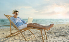 Happy,Man,With,Laptop,Talking,By,Mobile,Phone,On,Beach.