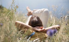 Middle,Aged,Woman,With,A,Backpack,Rests,On,The,Grass