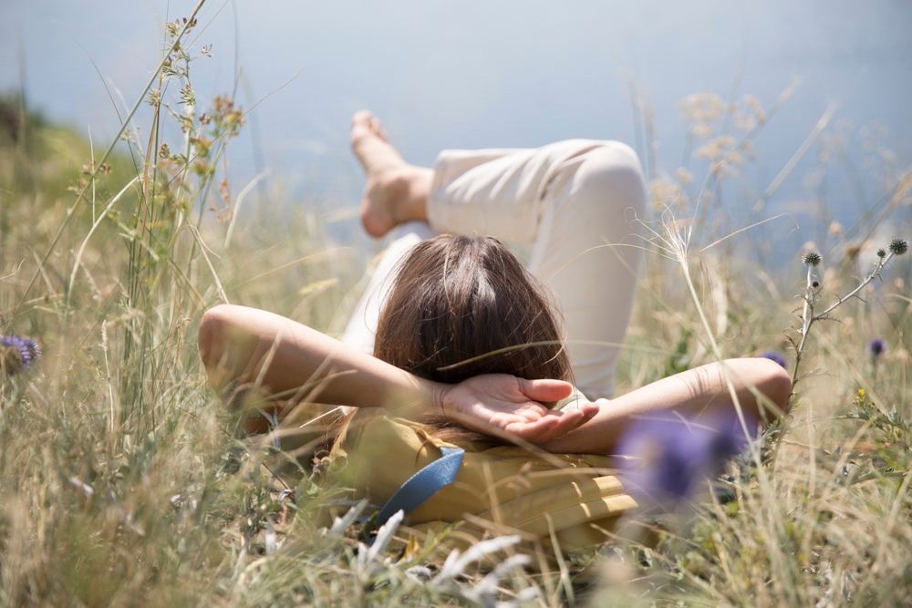 Middle,Aged,Woman,With,A,Backpack,Rests,On,The,Grass