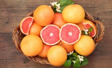 Wicker,Basket,With,Fresh,Grapefruits,And,Green,Leaves,On,Wooden