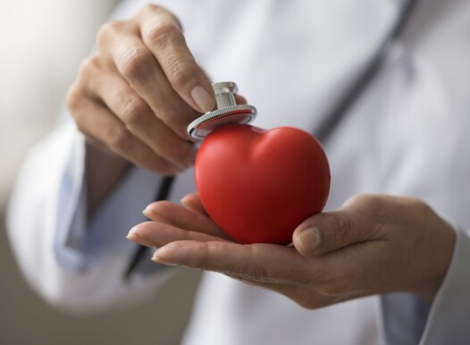 Hands,Of,Female,Cardiologist,Applying,Stethoscope,To,Red,Heart,Shaped