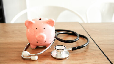 Piggy,Bank,,Stethoscope,And,Dollars,On,Wooden,Table,In,White