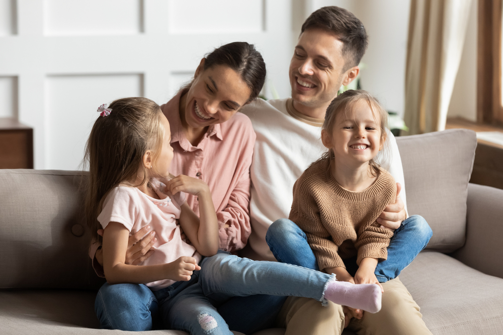 Happy,Young,Mother,And,Father,With,Two,Little,Daughters,Sitting