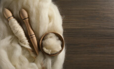 Soft,White,Wool,And,Spindles,On,Wooden,Table,,Flat,Lay.
