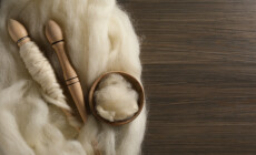 Soft,White,Wool,And,Spindles,On,Wooden,Table,,Flat,Lay.