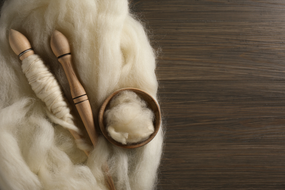 Soft,White,Wool,And,Spindles,On,Wooden,Table,,Flat,Lay.