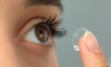 Woman,Putting,Contact,Lens,In,Her,Eye,On,Grey,Background,