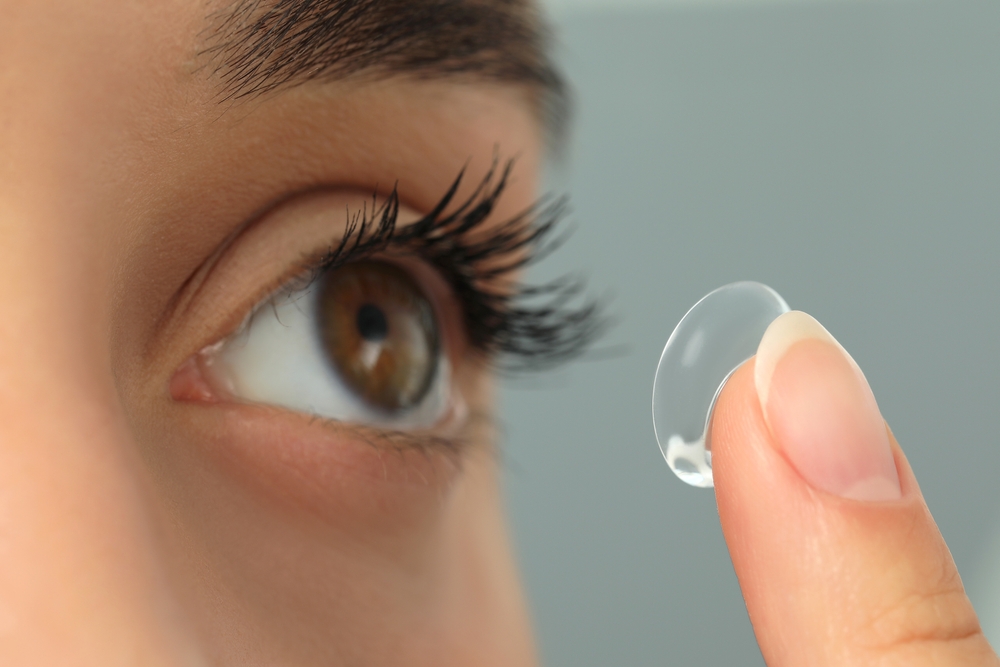 Woman,Putting,Contact,Lens,In,Her,Eye,On,Grey,Background,