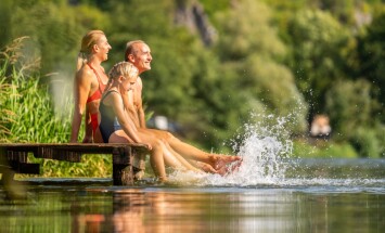 Family,Joyfully,Splashes,Water,While,Sitting,On,A,Wooden,Dock