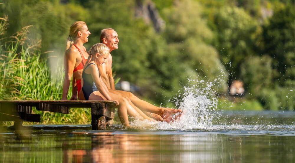 Family,Joyfully,Splashes,Water,While,Sitting,On,A,Wooden,Dock