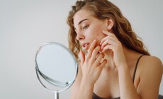 A,Beautiful,Woman,Looking,In,The,Mirror,,Touching,Her,Face