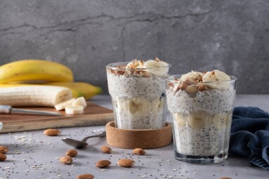 Overnight,Oats,In,Glasses,Topped,With,Banana,Slices,And,Almonds.