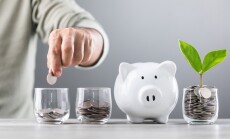 Man,Drops,Coins,Into,A,Glass,Jar,,With,Stacks,Of