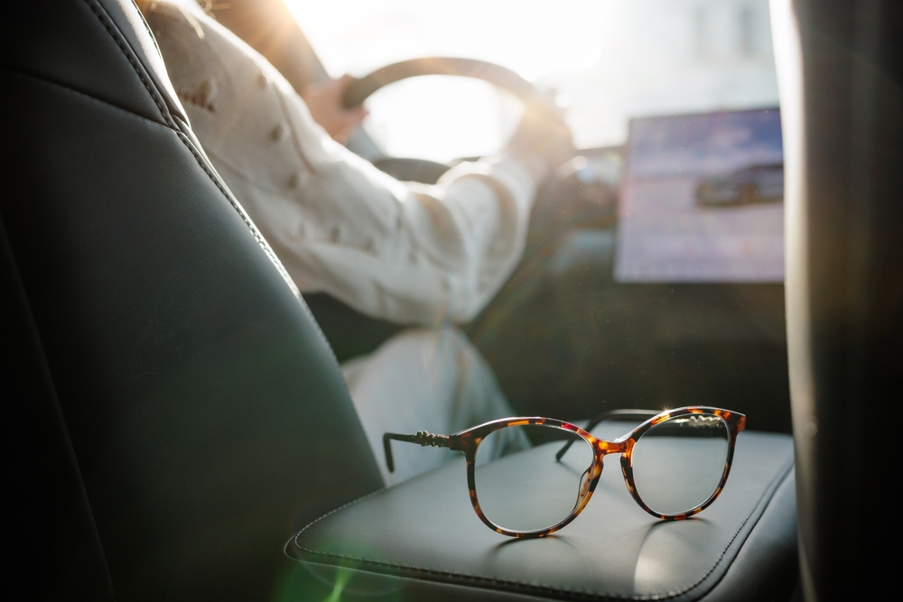 Eyeglasses,On,Car,Seat,With,Driver,In,Background,And,Sunlight
