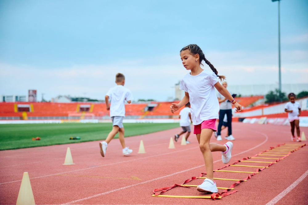 Little,Girl,Running,Over,Agility,Ladder,During,Exercise,Class,At